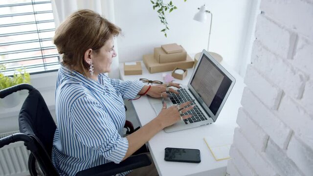 Disabled mature woman at home, working. Home office and leg amputee concept.