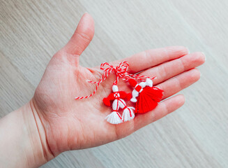 Bulgarian traditional spring decor martenitsa, holding in hand, wooden background. Baba Marta...
