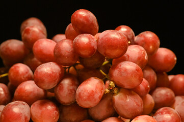 Ripe red grape. Pink bunch with black background.