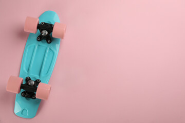 Skateboard on pink background, top view. Space for text