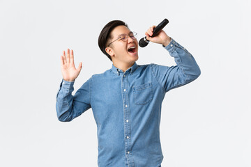 Lifestyle, leisure and people concept. Carefree asian guy in glasses and braces singing song at...