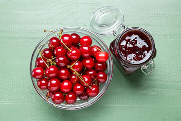 Jar of tasty cherry jam on color wooden background