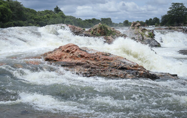 A close up view of the river rocks engulfed in the gushing water stream and frozen in frame of Cauvery near Mysuru in Karnataka, India.