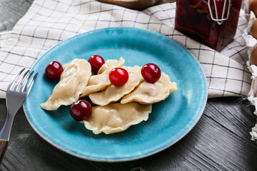Plate with tasty cherry dumplings on dark wooden background