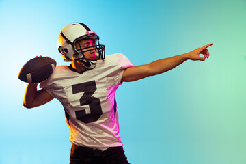 Portrait of American football player training isolated on blue studio background in neon light. Concept of sport, competition