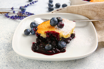 Plate with piece of blueberry cobbler and lavender on light background, closeup