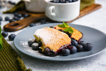 Plate with pieces of blueberry cobbler on light background, closeup