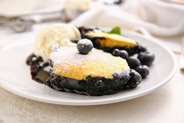 Plate with pieces of blueberry cobbler and ice cream on light background