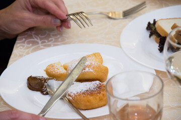 Woman eating fried cheesecakes with condensed milk, hands close-up. Delicious dessert in a cafe.