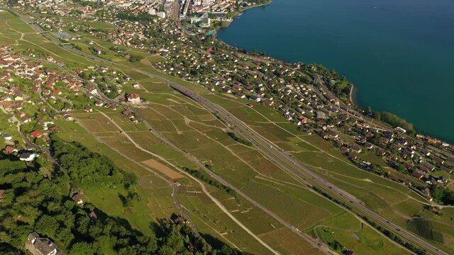 Aerial drone footage with a tilt up motion of the Vevey cityscape and the Lavaux vineyard by lake Geneva on a sunny summer day in Switzerland
