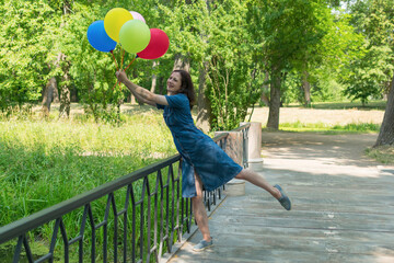 Young woman with colorful air balloons outdoors, happiness concept.