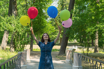 Young woman with colorful air balloons outdoors, happiness concept.