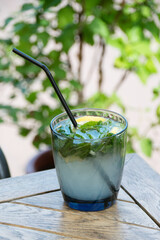 Mojito with ice in a glass beaker close-up on a wooden table on the summer playground of the bar