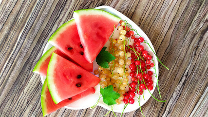 Berries. Slices of watermelon and currant berries lie on a plate in the shape of a heart.