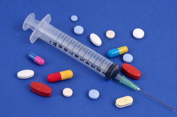 Seringue entourée de médicaments en gros plan sur fond bleu
