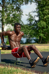 Athlete doing push-ups on the sports ground, African American athlete doing push-ups on outdoor gym equipment, sports lifestyle, striving for success