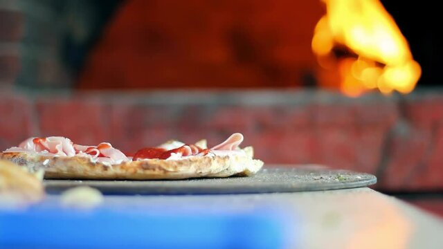 Chef Making Sandwich in front of Wood Fired Brick Oven - Hand Sprinkles Grated Cheese on Sandwich