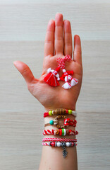 Bulgarian traditional spring decor martenitsa bracelets, holding in hand, wooden background. Baba...
