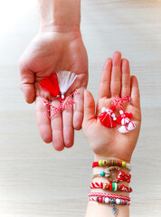 Bulgarian traditional spring decor bracelet martenitsa, holding in hand, wooden background. Baba Marta holiday, backdrop.
