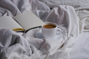 Coffee with milk and a notebook in bed. Breakfast in bed. Interior. Cosiness.