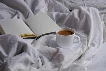 Coffee with milk and a notebook in bed. Breakfast in bed. Interior. Cosiness.