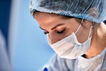 Female surgeon in operating room close-up, woman doctor face during operation