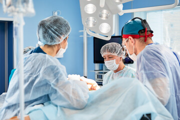 Surgeons during surgery with breast implants in their hands, installation of breast implants,...