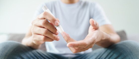 Man using lancet on finger for checking blood sugar level by Glucose meter, Healthcare and Medical,...