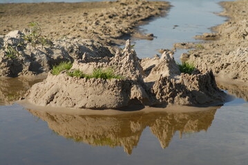 Background with a sandcastle and its reflection in the water. Summer vacation concept.Children entertainment.Text place.