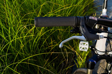 bike in the foreground, black rubber handle,frame,brakes active lifestyle, .сycling, green grass...