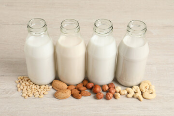 Different nut milks on white wooden table