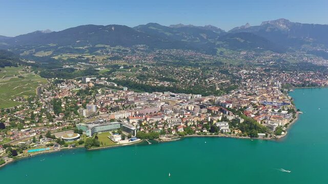 Aerial drone footage with a rotation motion of the Vevey cityscape by lake Geneva on a sunny summer day in Switzerland