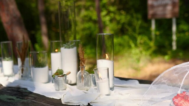 Fruit slices plate under fly mesh food tent cover on wedding party banquet catering outdoors in forest. Dining table decorated in boho style with candles, white cloth, flowers served with tableware.