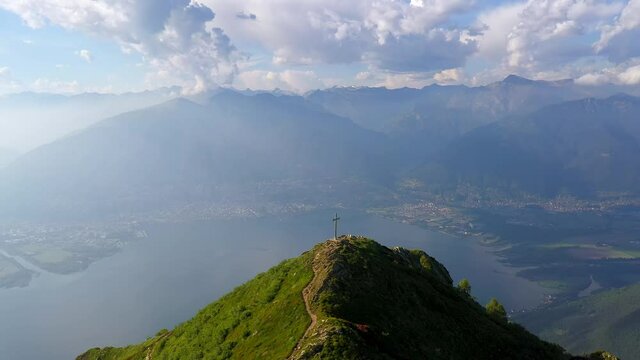 Dramatic aerial drone footage of the Monte Gambarogno summit with its cross overlooking the lake Maggiore and the Locarno city in Canton Ticino in Switzerland