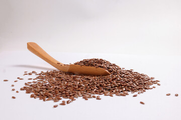 Flex seed flaxseed closeup wooden scoop spoon laid on top with pile of seeds