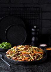 Azu - traditional tatar stew. Beef meat stew with vegetables and pickles on a black background, selective focus