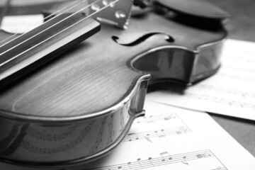 Beautiful violin and note sheets on table, closeup. Black and white tone