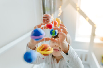 Little girl playing with toy planets made by herself from colorful molding clay indoor