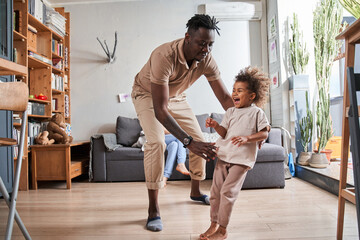 Funny parent and cute little child girl laughing in modern living room