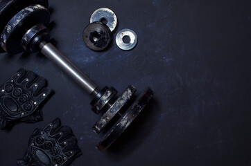 Obraz na płótnie Canvas old dumbbell with gloves dark background with empty space minimal style,sports equipment