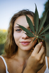 Portrait Of A Young Girl Holding Green Hemp Leaves Outdoor In Summer