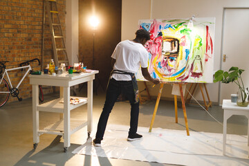 Obraz premium African american male painter at work painting on canvas in art studio
