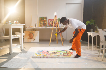 African american male painter at work painting on canvas in art studio
