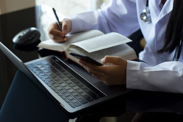 Doctor woman read book and using mobile phone, work with laptop computer 