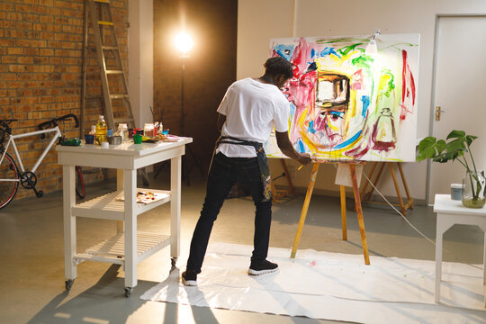 African american male painter at work painting on canvas in art studio