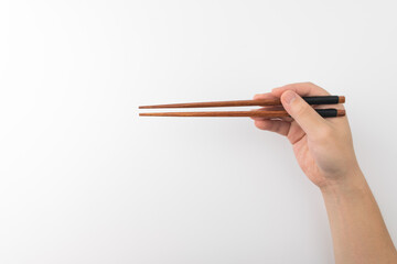 Hand holding wooden chopsticks on a white background