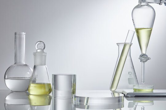 Assorted laboratory glassware equipment showcase with oil on white backround. Stage showcase cosmetics on glass pedestal modern in laboratory equipment. Minimal concept. 