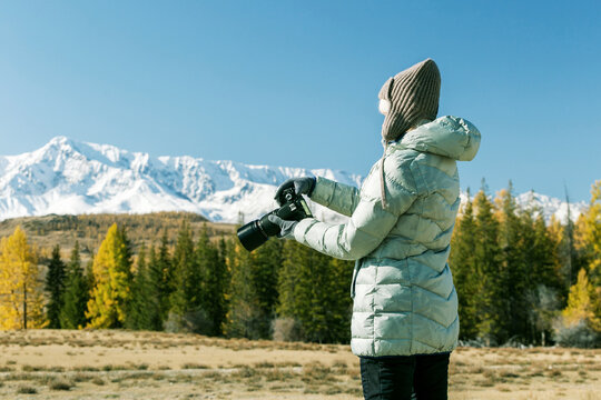 Travel tourist woman photographer taking pictures with camera of nature landscape in autumn mountains.