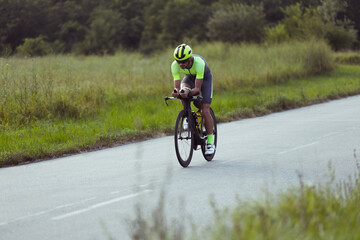 Young male triathlete riding a bicycle on the open road. Professional sportsman is engaged in...