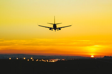 Airplane landing on the runway during sunset and dusk